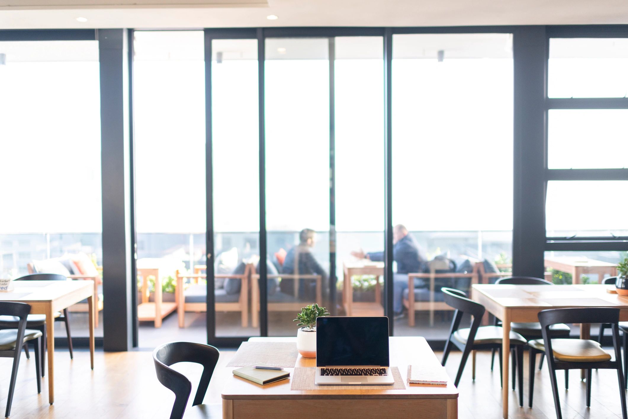 Table with notebook and laptop inside rooftop cafe